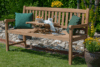 Gartenbank aus Holz mit Tablett und grünen Kissen